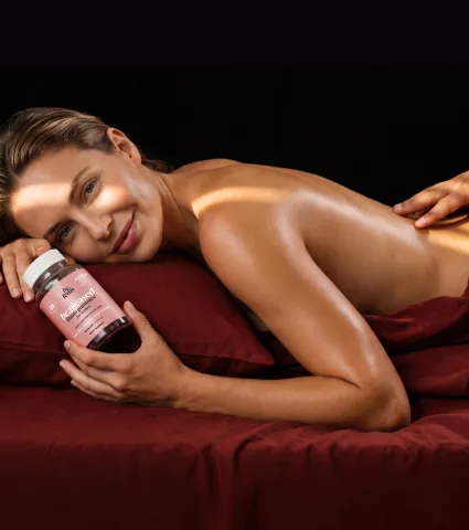 Woman in bed holding a bottle of be.pleased libido gummies